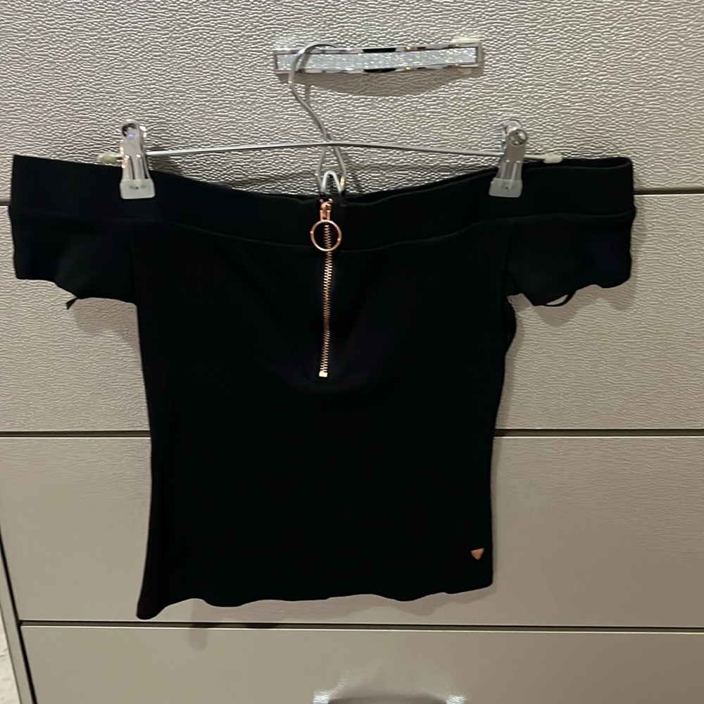 This is a black off the shoulder Guess top with a rose gold zipper on the top.